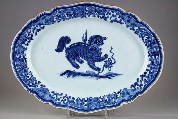Large dish with round edge in white blue porcelain bearing a decoration of a Fo dog or Buddhist lion playing with one of the eight precious objects the sapphire symbolizing wealth 
 - China Qianlong period 1736/1795