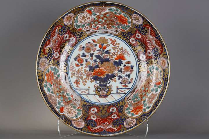 Important dish in porcelain of Japan called Imari decorated in  underglaze blue  iron red gold  and green enamels of a flowery vase in its center and on the wing of kara-shishi in three reserves and three cranes .
Japan  Arita kilns period Edo 18th century          (diam 56cm)